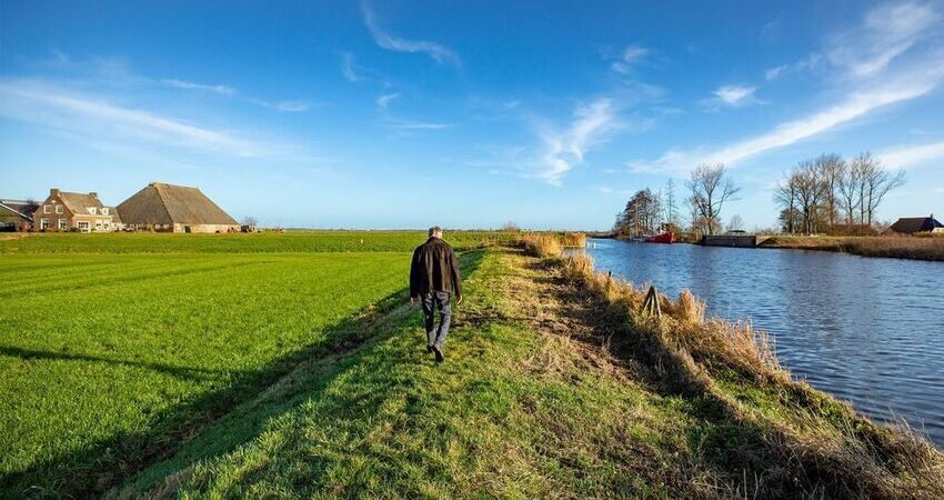 Foto van lopende man in een veenweidelandschap
